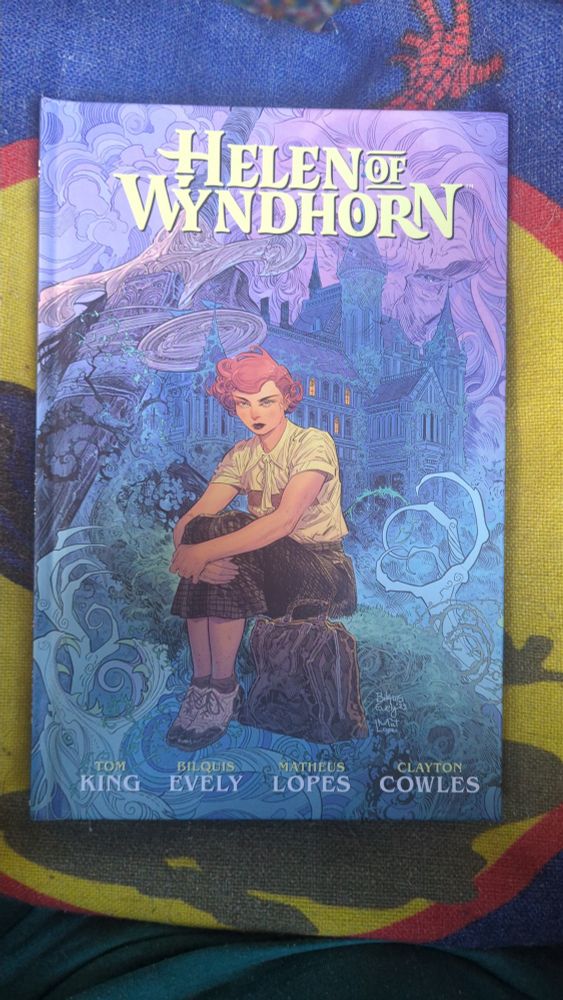 The cover of Helen of Wyndhorn showing a young ginger woman sat on a log before a large mysterious house