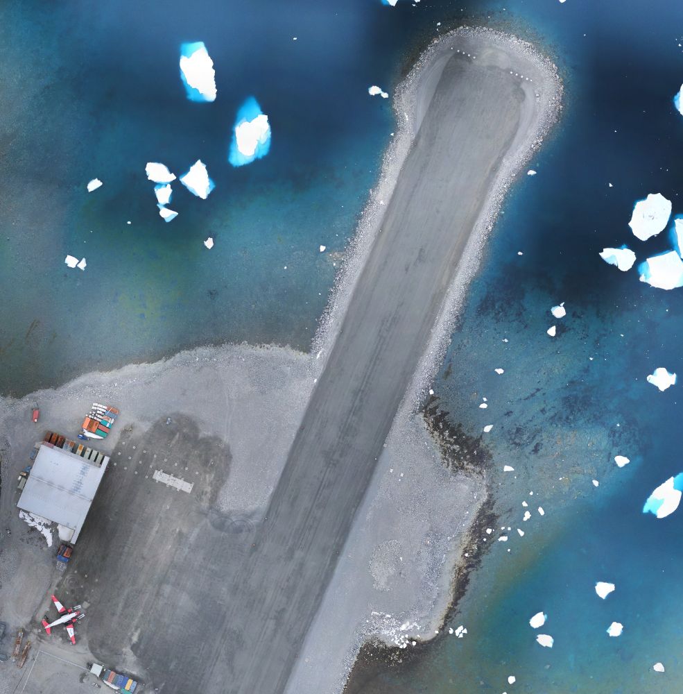 A zoomed in portion of the image, showing the northern end of the runway and the hangar. A white and red plane can also be seen, parked next to the hangar.