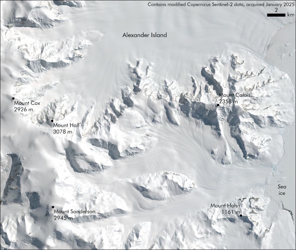 A satellite image of some of the highest peaks on Alexander Island. The image is white and largely snow-covered, with small areas of rock outcrop visible in some areas. The image labels 5 mountains, including Mount Hall at 3078 metres tall (the highest mountain on the island). 