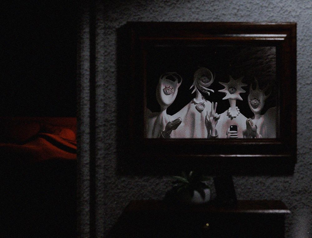 a stylized 3d render. on a wall hangs a mirror, with four demons/angels with one eye each mugging the camera. a person sleeping in a bed is visible in the background.