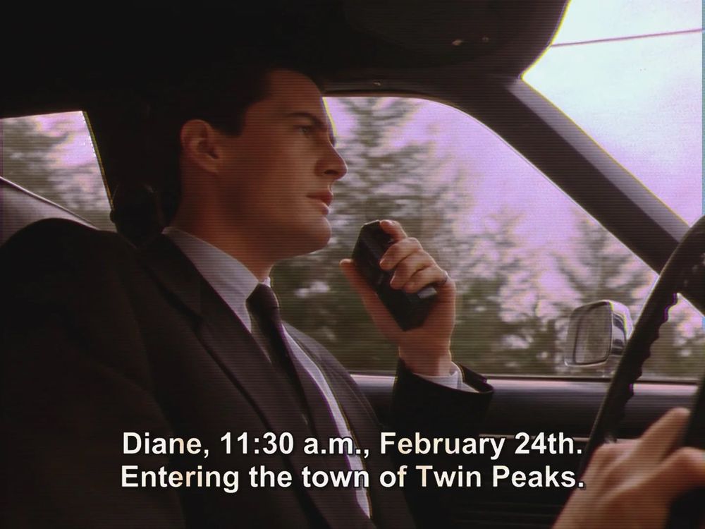 Screenshot of Agent Dale Cooper driving speaking into his tape recorder, captioned: Diane, 11:30 a.m., February 24th. Entering the town of Twin Peaks.