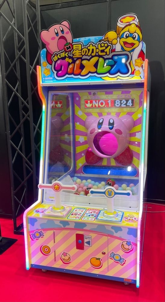 A Japanese Kirby arcade machine. Two players can push down levers to aim plastic balls into Kirby's mouth.