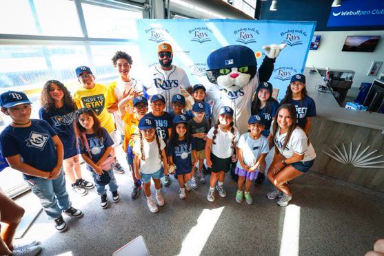 Alt text for all 4 photos: Junior Caminero and young fans at a Spanish Reading with the Rays event.