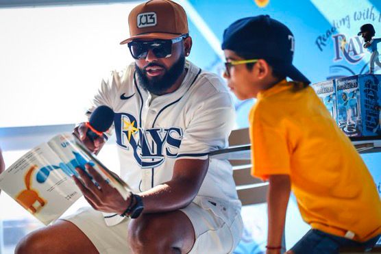 Alt text for all 4 photos: Junior Caminero and young fans at a Spanish Reading with the Rays event.