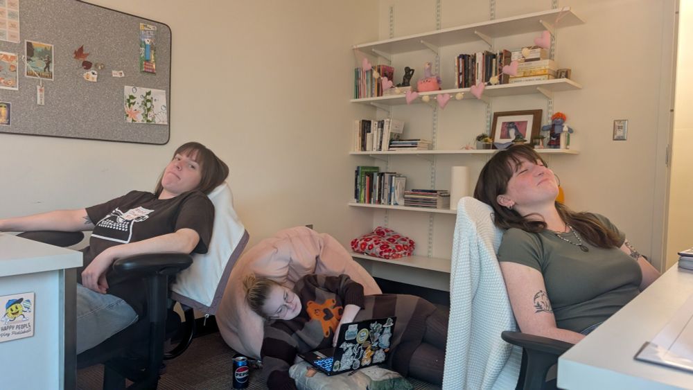 The three fates of graduate studies: fatigue, dismay, and burnout sit in an office in various states of repose.