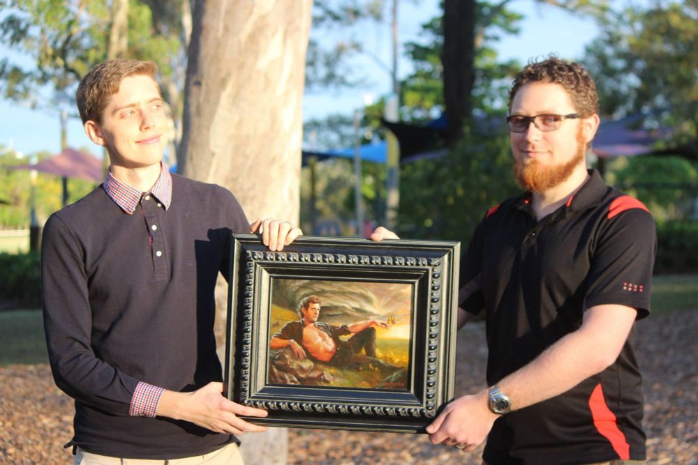 Two friends exchange the framed original painting of the previous image in a public park.