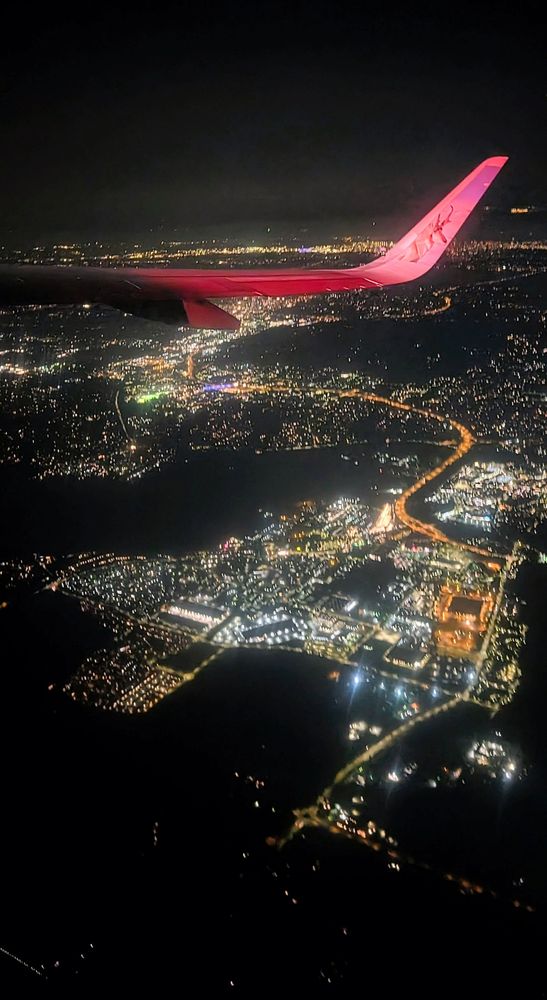 Aerial view of Seattle at night with an airplane wing at the top illuminated by red navigation lights