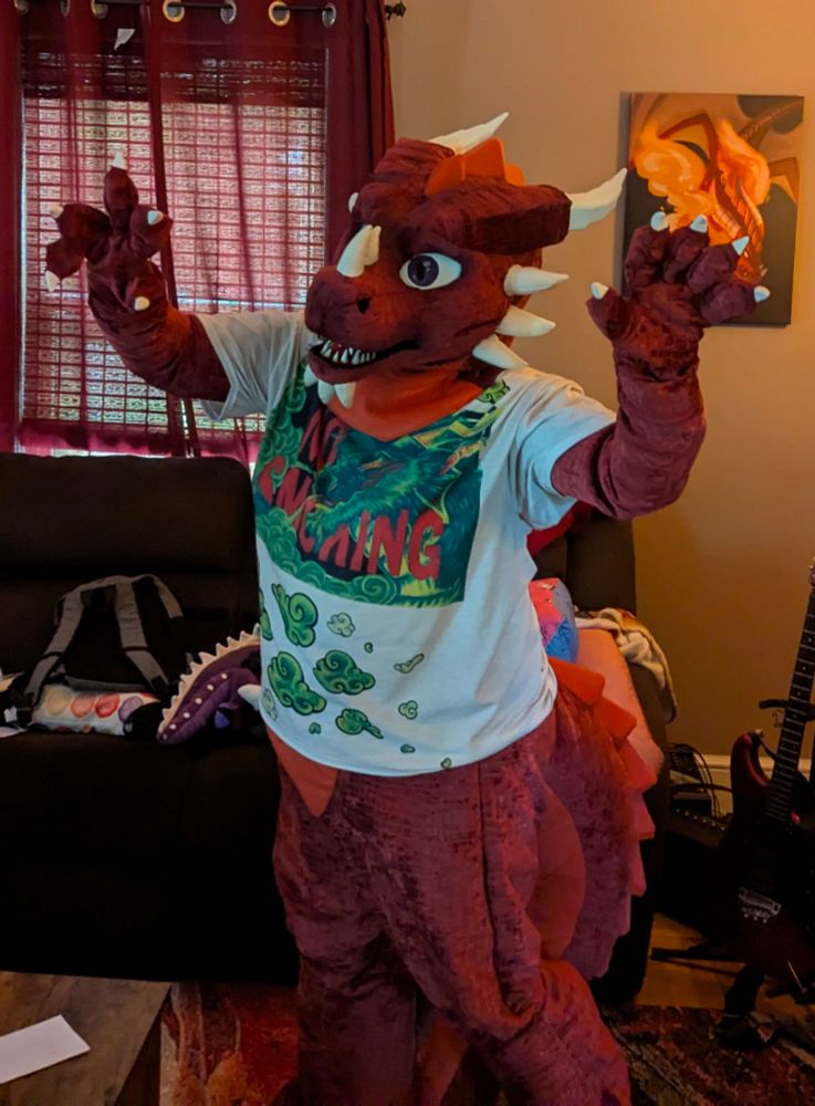 A red dragon in mostly full fursuit posing at the camera 