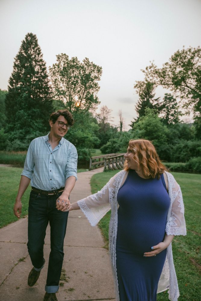 My wife, visibly pregnant, guiding me by hand down an outdoor park path