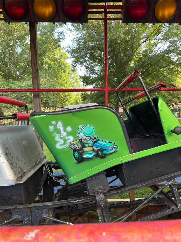 A green roller coaster cart with Yoshi in a racing cart painted on the side
