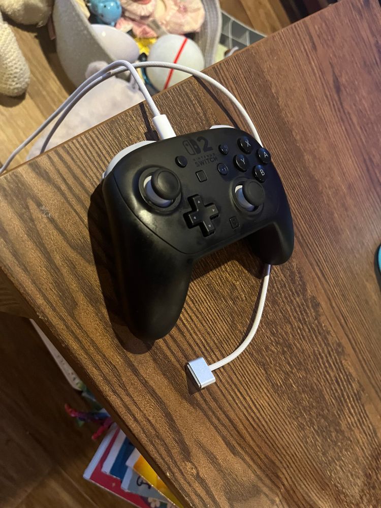 A switch two pro controller plugged into the USBC end of a mag safe mac book charger. 