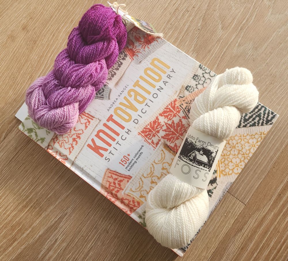 Purple gradient and natural yarns shown on a book (Knitovation Stitch Dictionary by Andrea Rangel)