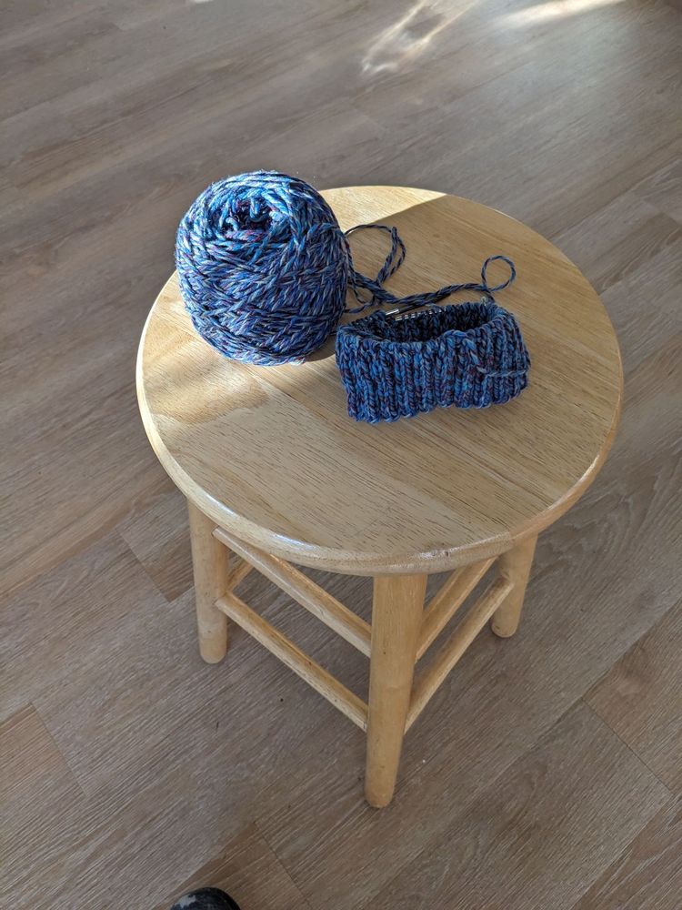 The beginnings of a blue knit hat on the needles. 