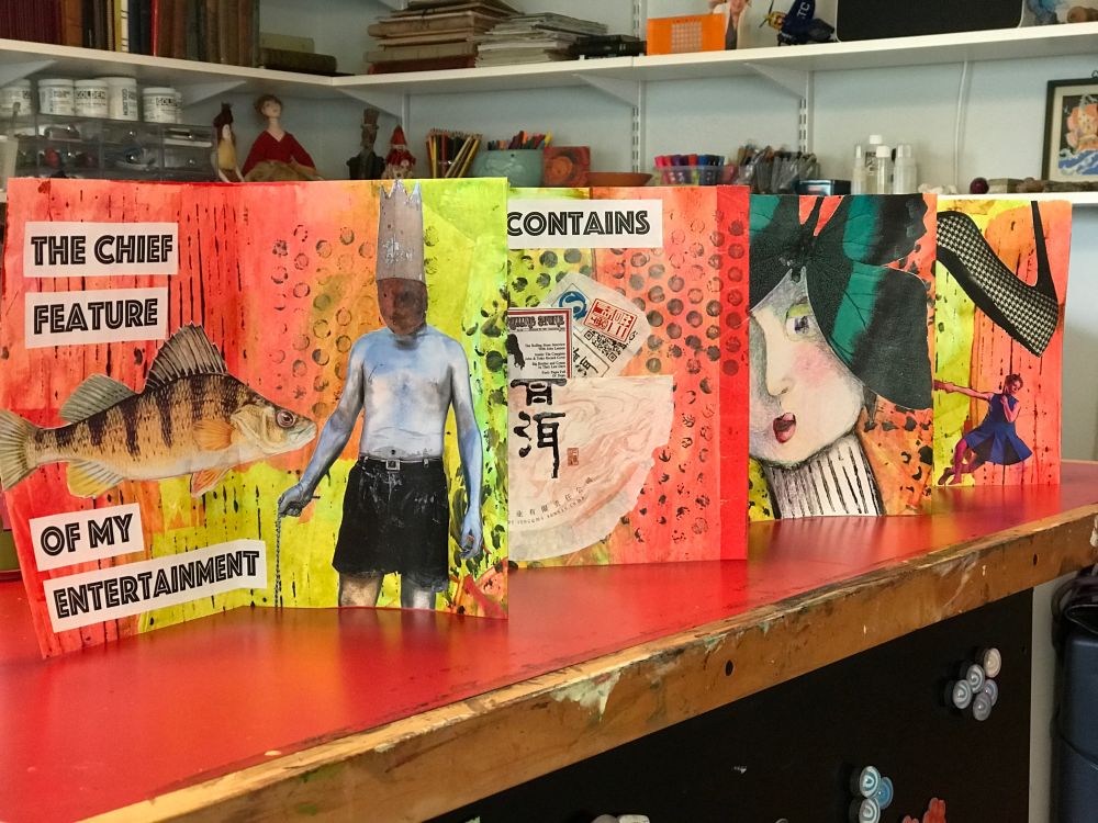 Collage art in the form of an accordion book—full piece unfolded and pictured standing upright on a red table.