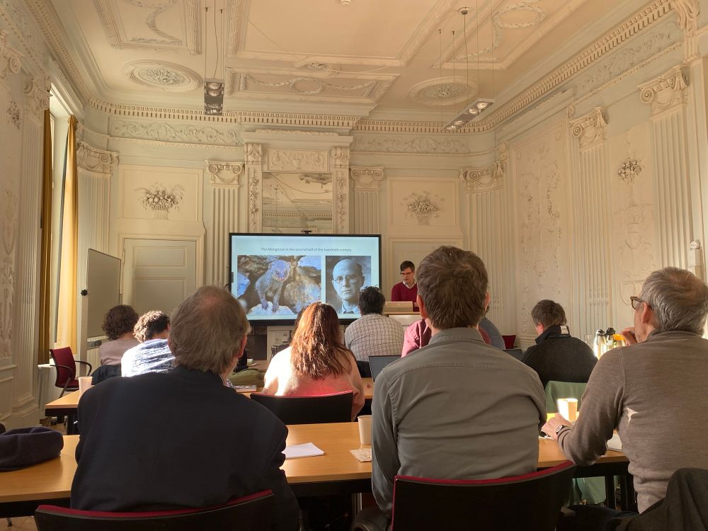 Vincent Bijman and audiences at the Moving Animals conference. Slides show a mongoose and the ecologist Charles Elton.