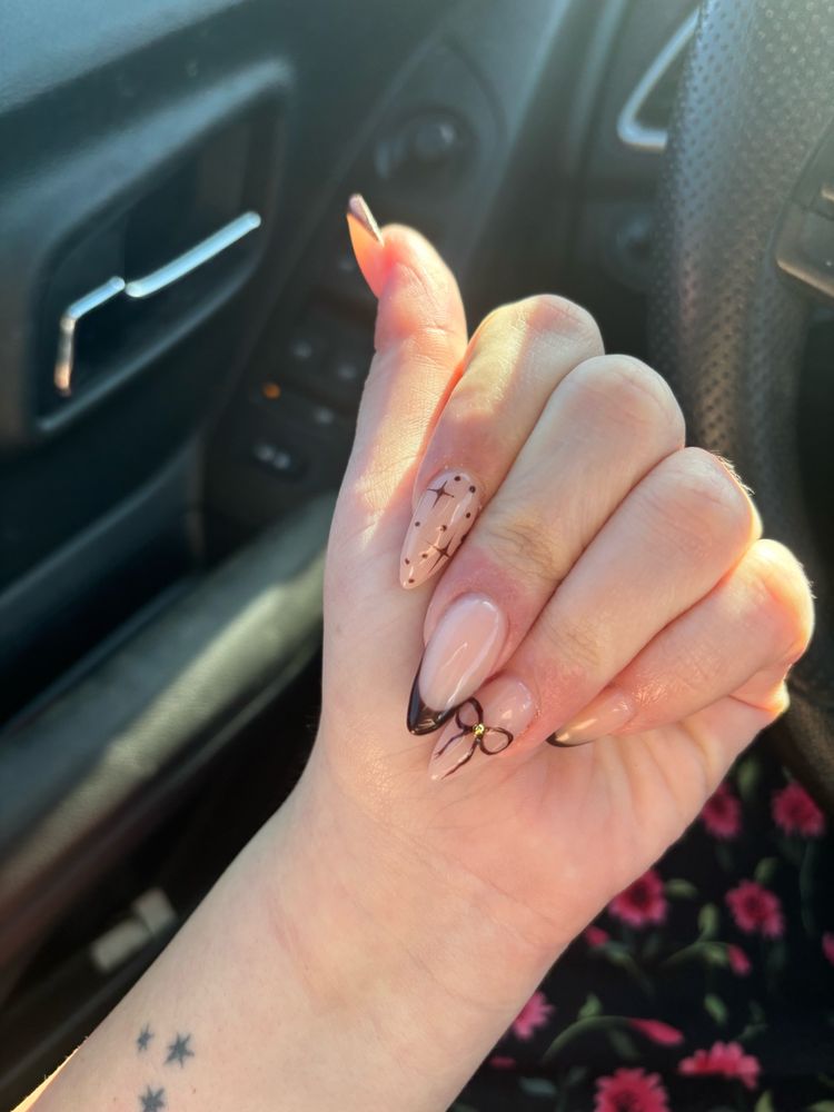 A photo of my acrylic nails. They’re pointy almond shape and brown French tips. There’s a bow on my ring finger and like sparkly stars on my pointer 