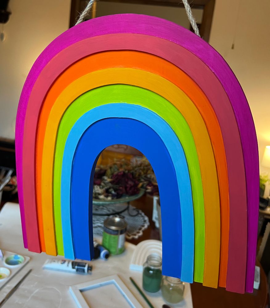 A wooden rainbow hand painted in the colours of the rainbow.