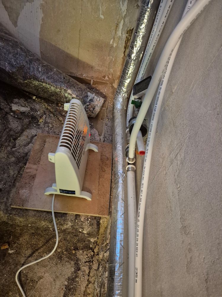 Elektrischer Frostwächter auf einer Fliese vor Rohrleitungen 