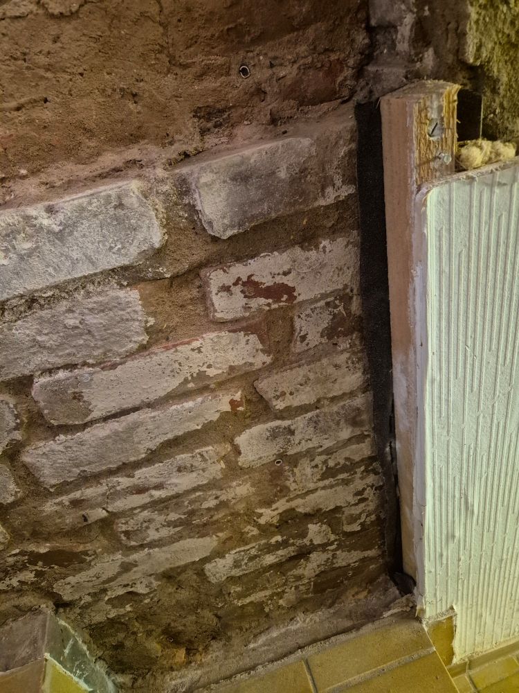 Rohes Mauerwerk entlang einer Treppe, daneben ein Stück, das noch verkleidet ist.