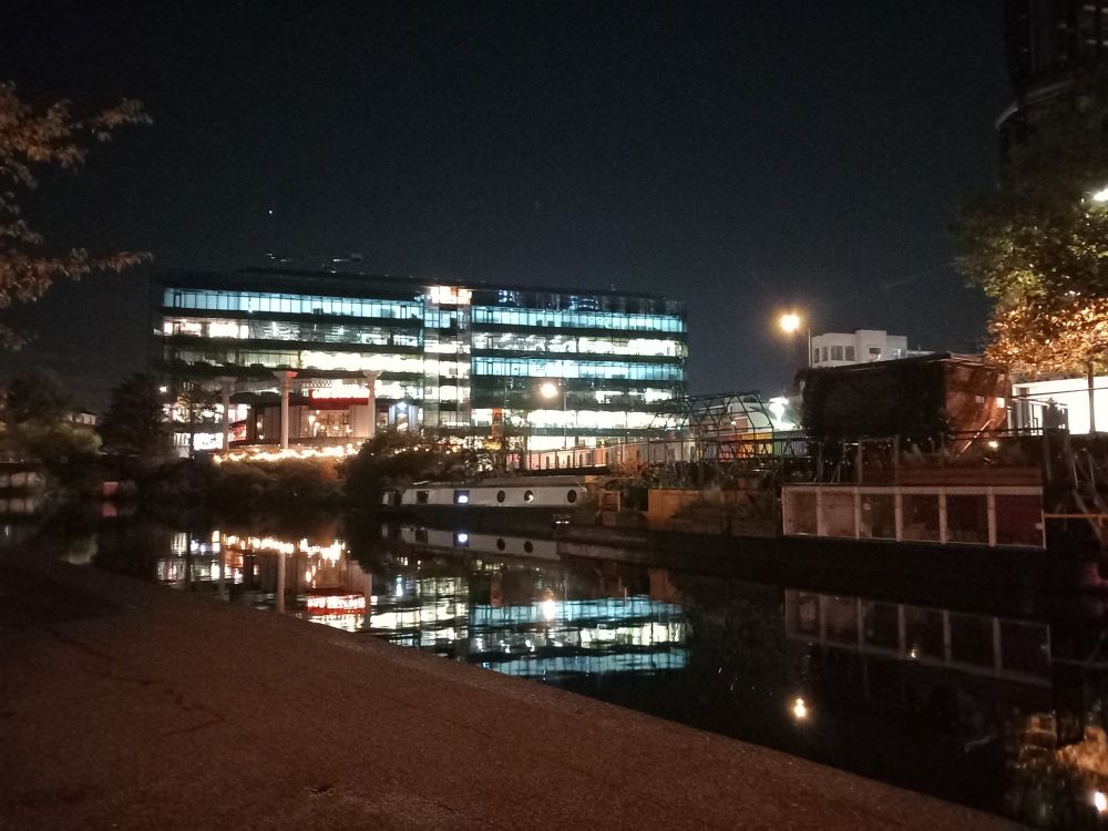 The lights of a building in London gleaming into the night and overlooking a canal.