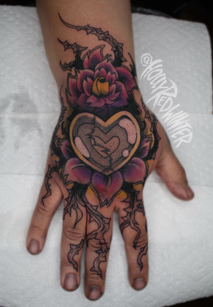 A tattoo on the back of a hand of the cracked heart locket from mystery skulls animated 