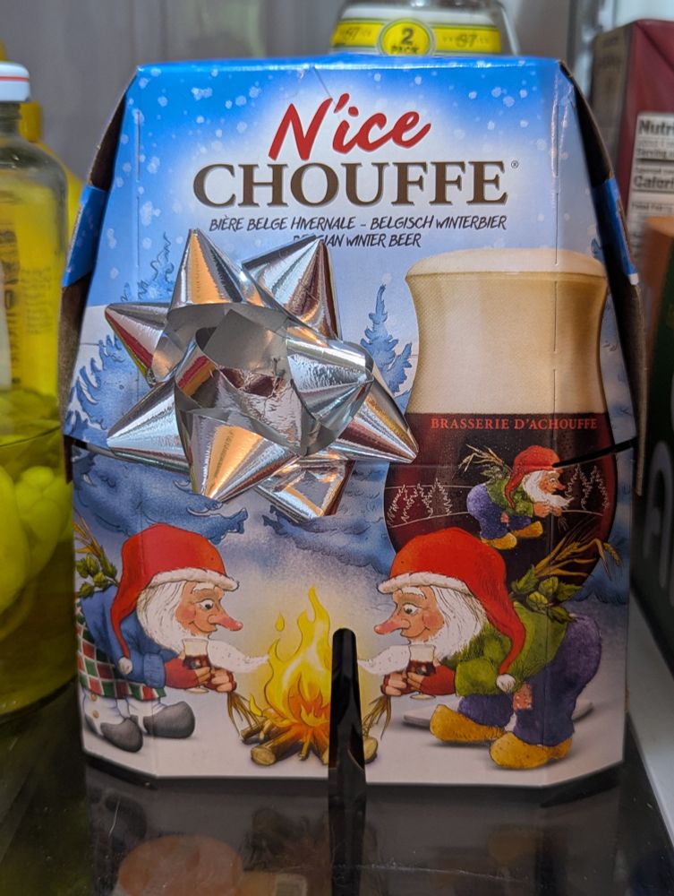 A 4-pack of the Belgian winter beer N'ice Chouffe, which has an illustration of gnomes by the fire drinking beer and wearing Santa hats.