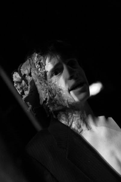 A young actor wearing a prosthetic that shows half his head exploded