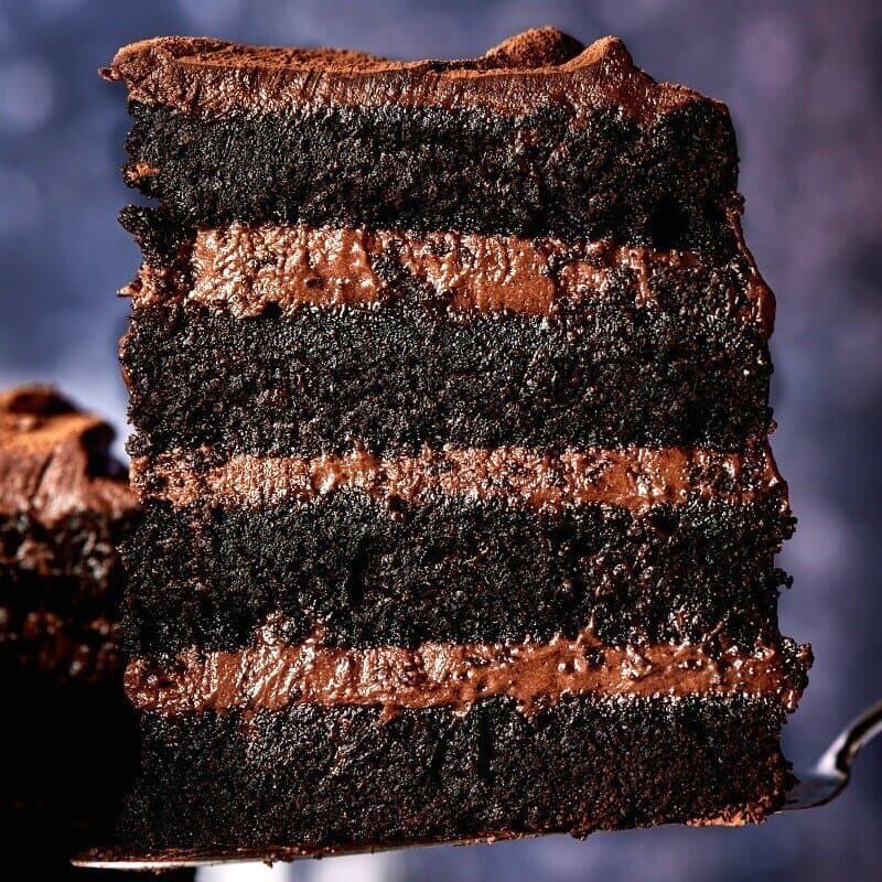 Large piece of four-layer chocolate cake with chocolate frosting.