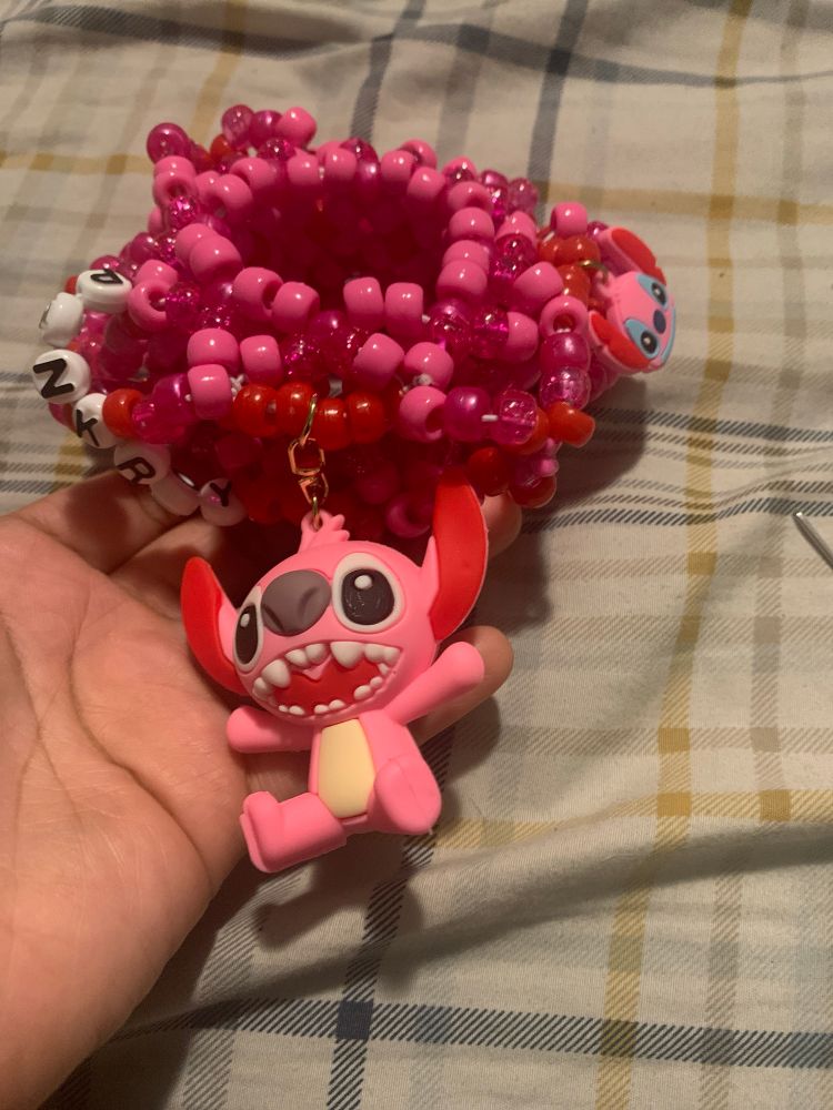 Pink and red kandi bracelet with pink stitch charms from lilo and stitch.