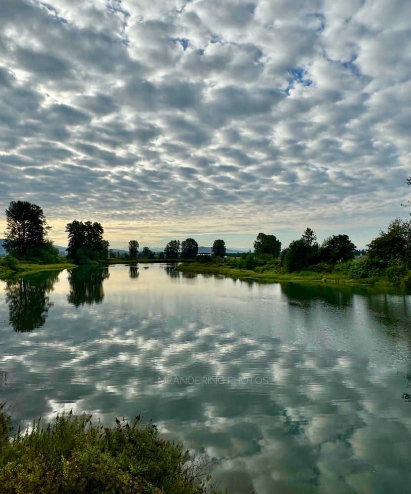 Soft cobblestone looking clouds are duplicated in the waterway as if a stoned walkway was being moulded. 