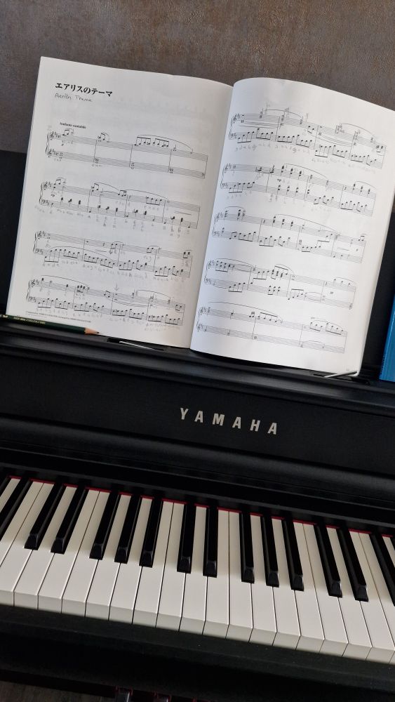 Ein Klavierausschnitt mit einem aufgeklappten Notenbuch zu dem Lied 'Aerith Theme' 