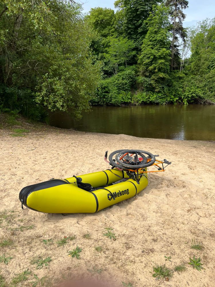 Packraft gonflé avec un vélo démonté dessus. 