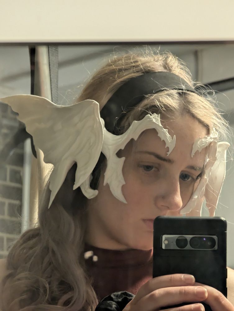 Mirror selfie of a woman with long grey hair and a cosplay headpiece based on the Au Ra from Final Fantasy XIV 