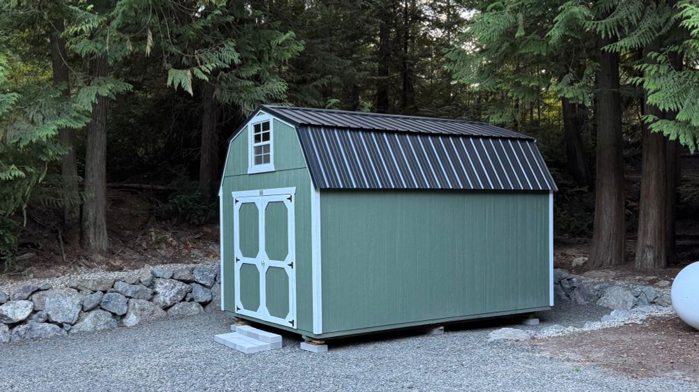 The same area, but with the carport demolished and all the junk hauled away. In its place is a rock retaining wall, new gravel, and a green lofted barn shed.