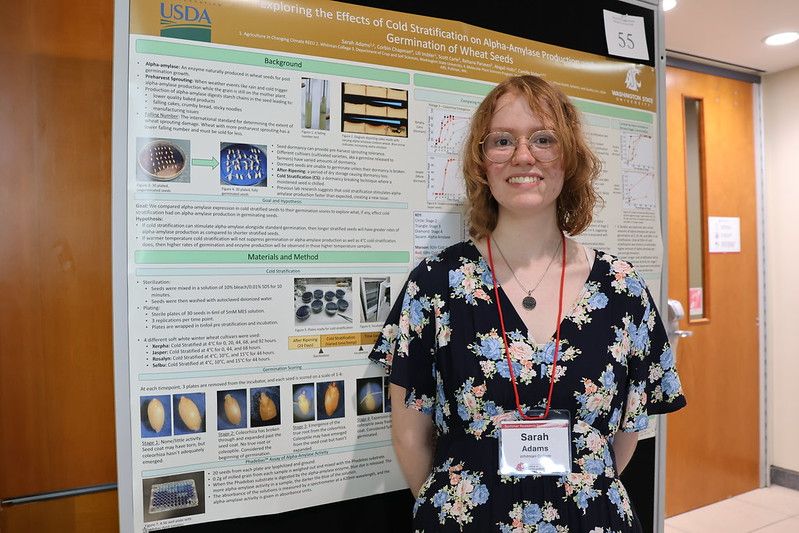 A person stands in front of an academic poster that is covered with lots of text and images.