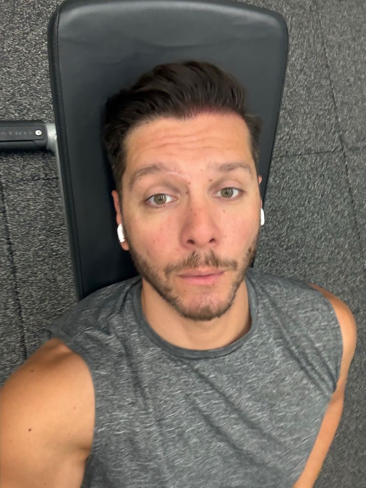 Man leaning back on incline bench in the gym with exhausted expression on face. 