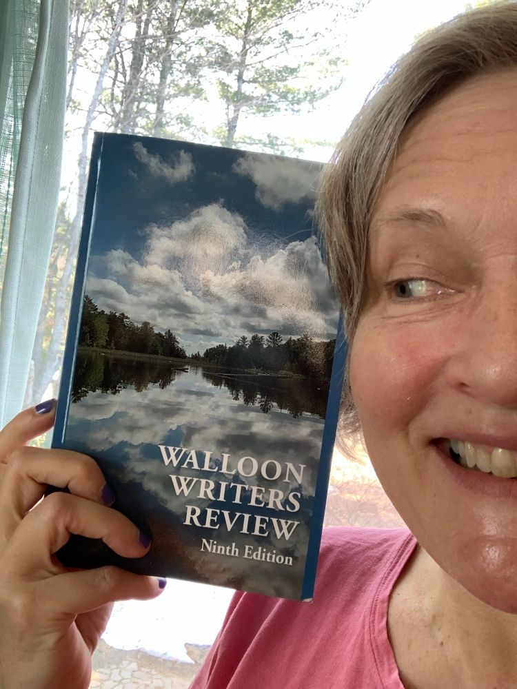Smiling face next to a hand holding a book titled Walloon Writers Review, Ninth Edition.