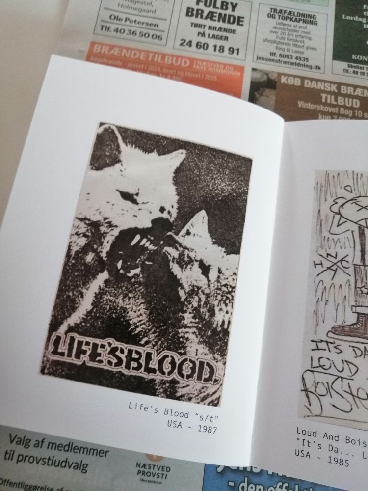 En bog slået op på en side med sort-hvid gengivelse af en kassette-cover fra hardcorebandet Life’s Blood. På billedet ses en collage med to dyr (ulve eller hunde) og teksten “LIFE’S BLOOD”. Under billedet står: “Life’s Blood ‘s/t’ USA – 1987”.