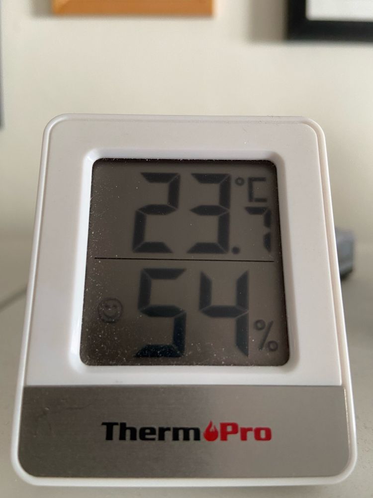 In my living-room, a digital thermometer showing the temperature as 23.7C with 54% humidity.