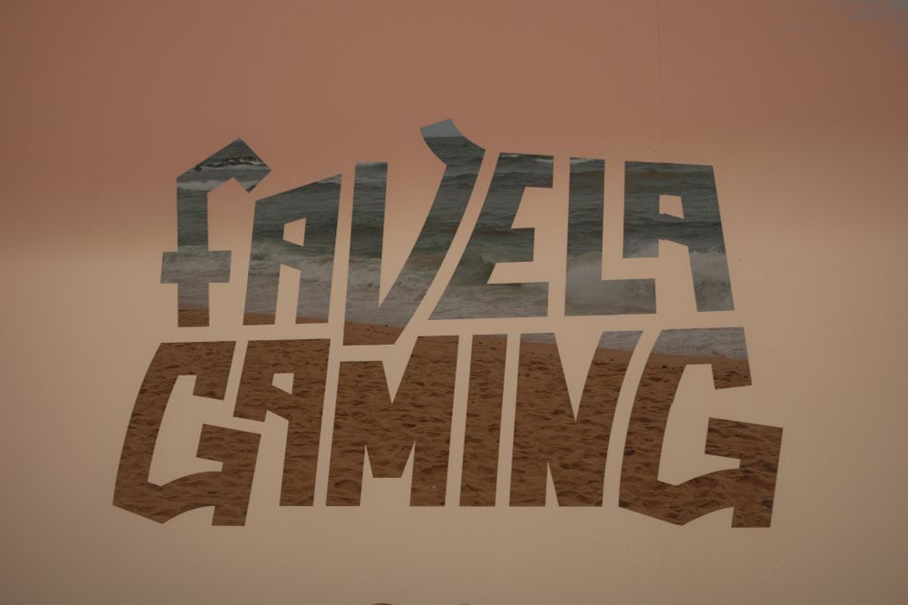 dupla exposição com a palavra "Favela Gaming" em destaque e dentro dela, imagem de uma praia