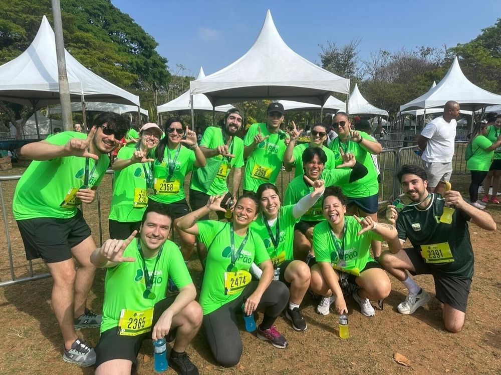 13 pessoas com camisetas verde limão da corrida do Pão de Açúcar, número de peito e medalhas, posando para a foto fazendo o L de LOUD com as mãos. Foto tirada no Ibirapuera, depois de terminarmos a corrida.