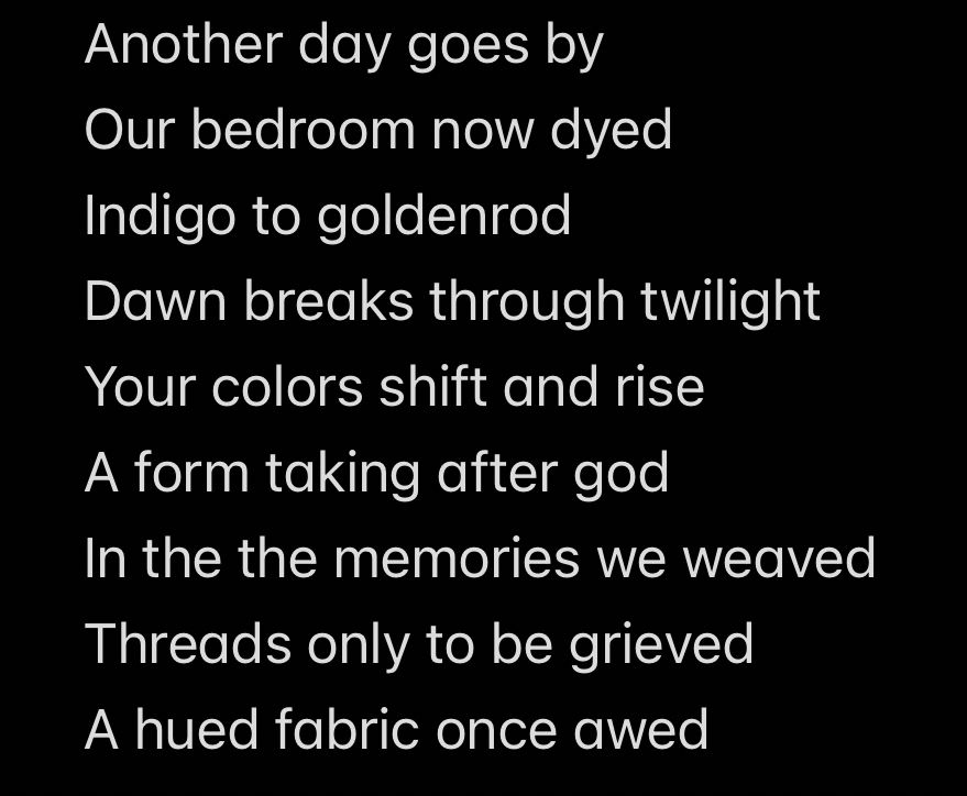 Text on screen says:

Another day goes by 
Our bedroom now dyed 
Indigo to goldenrod 
Dawn breaks through twilight 
Your colors shift and rise 
A form taking after god 
In the the memories we weaved 
Threads only to be grieved 
A hued fabric once awed 