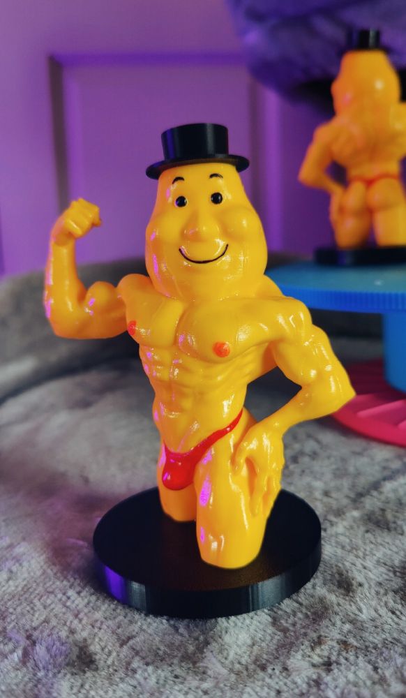 Mr Tayto painted sculpt. He has a pleasant face, yellow skin and a red thong. He is glistening.