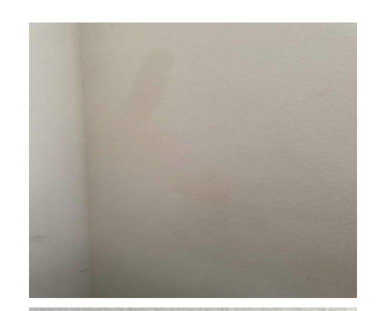 A white wall. There's a shadow of some sort at the top. The wall isn't damaged. It's just a white wall. I have no idea what they're trying to prove.