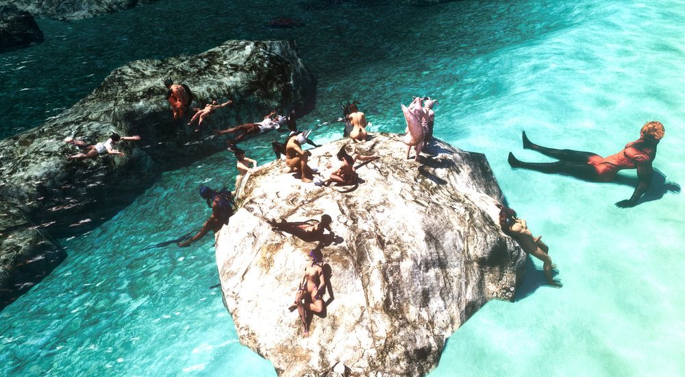 One angle of a group of friends hanging out on a rock by the sea, naked and loving their time in the sun.