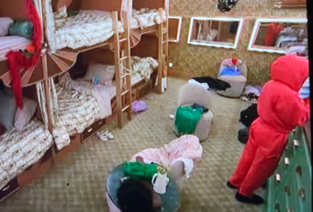 Ashley from big brother season 27 wearing an all hot pink long sleeve sweatsuit in the train room turned around facing the mirror
