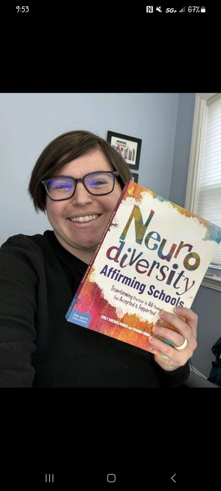 image of a woman with glasses and short hair wearing a black shirt holding a copy of "Neurodiversity-Affirming Schools: Transforming Practices So All Students Feel Accepted and Supported" 