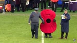 An embarrassing low point in War Christmas where Tranmere Rovers trotted out a (presumably young) mascot in a full body poppy costume. Guided bh a man in military uniform.