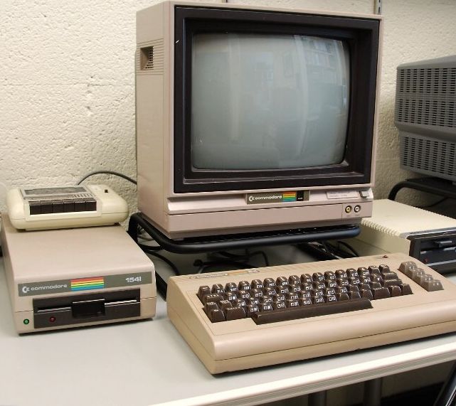 A Commodore 64 sitting on a desk in all its beige glory.