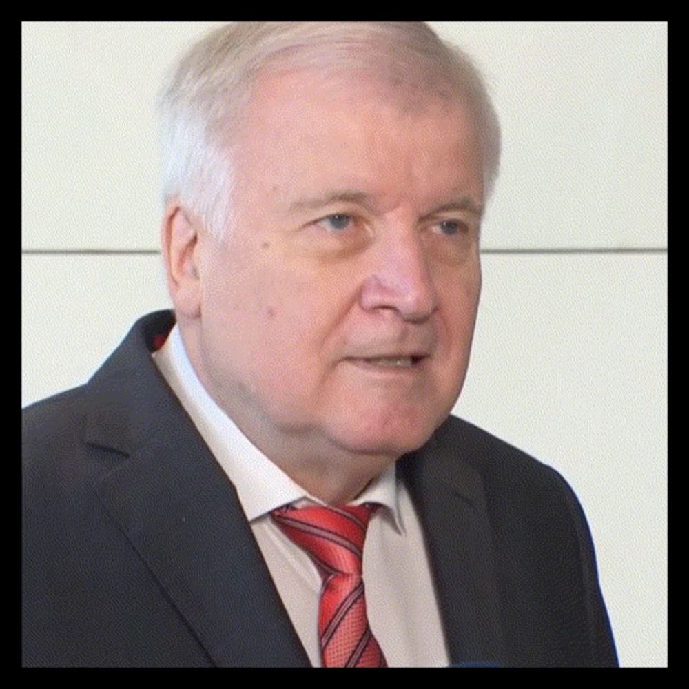 an older man in a suit and tie looks at the camera